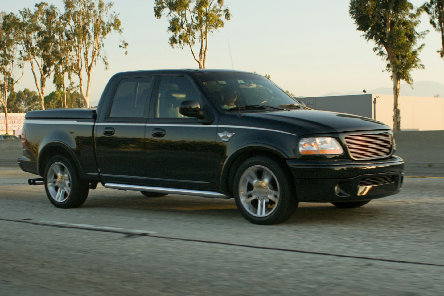 A black pickup truck driving on a multi-lane highway.