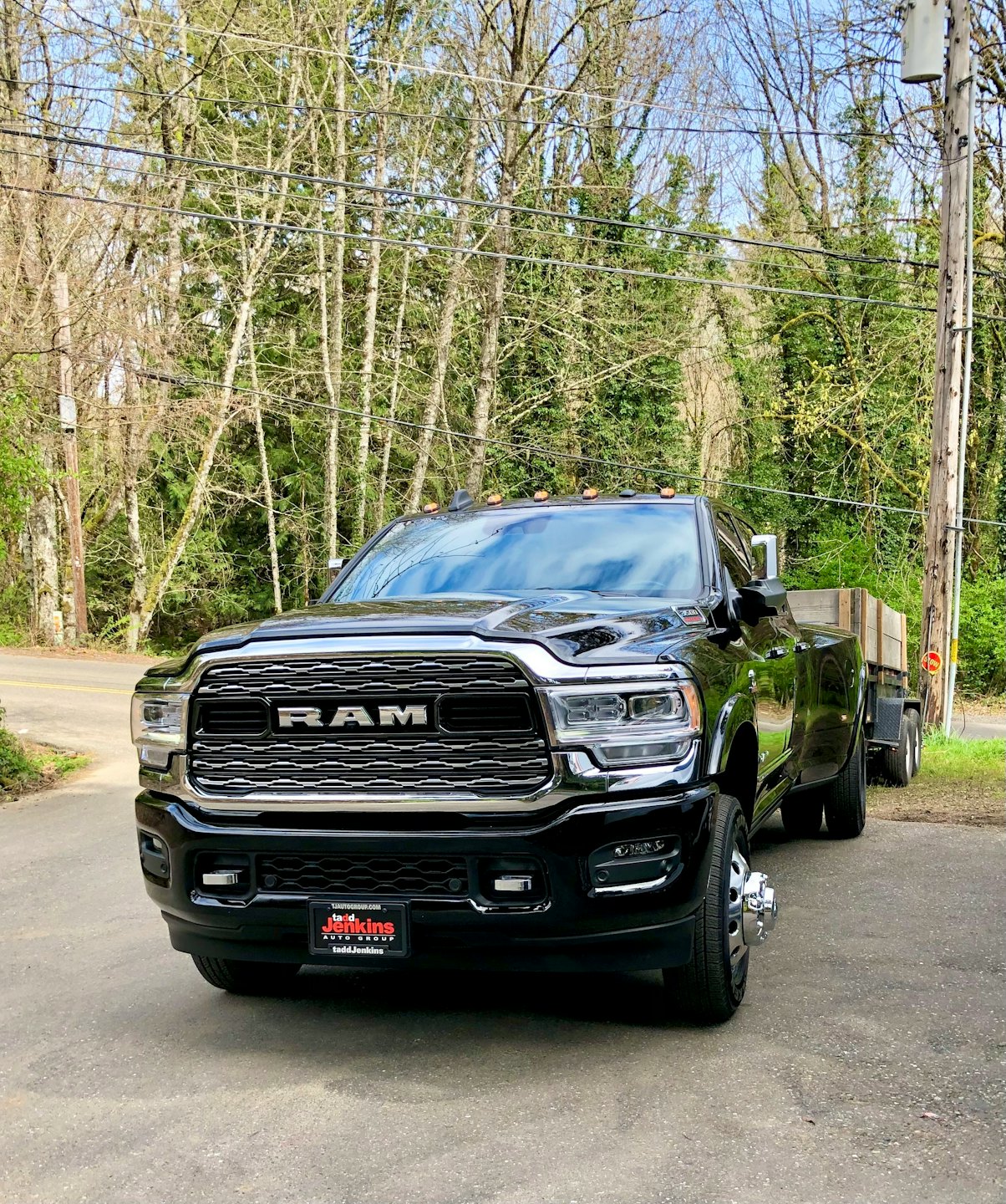 Black Ram dually truck pulling a wooden utility trailer.