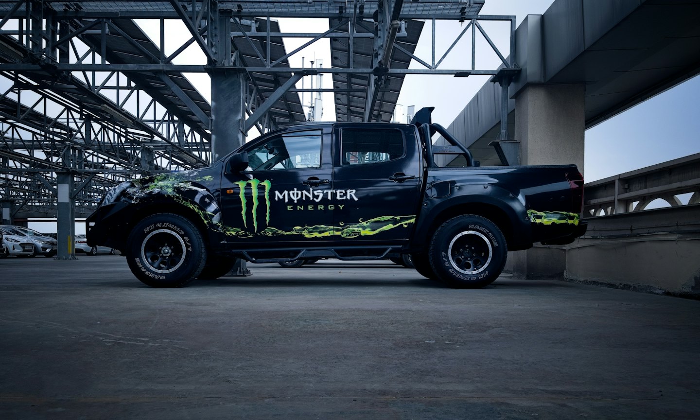 Black pickup truck with bright green logos parked under concrete structure.