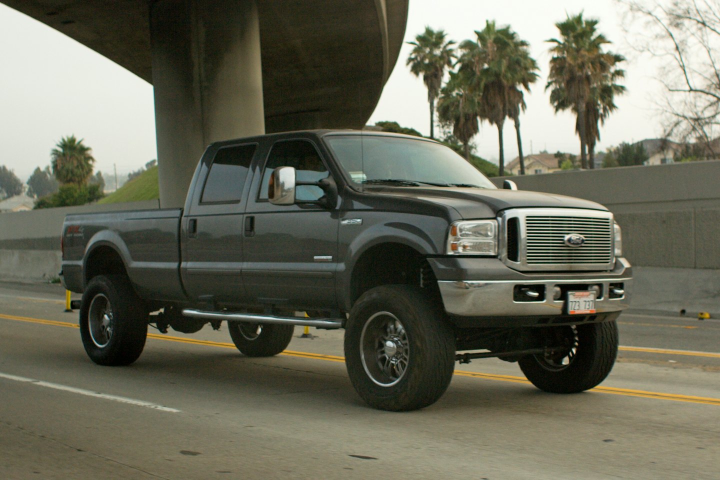 A dark gray Ford F-250 pickup truck drives on a highway.