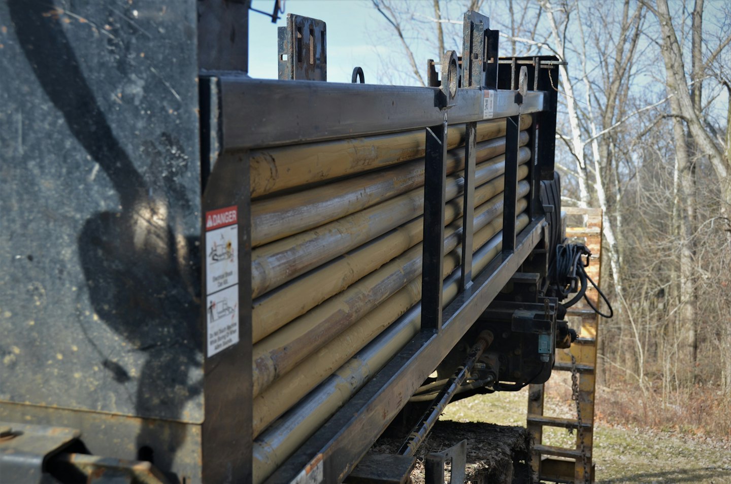 A flatbed truck carrying stacked pipes parked outdoors.