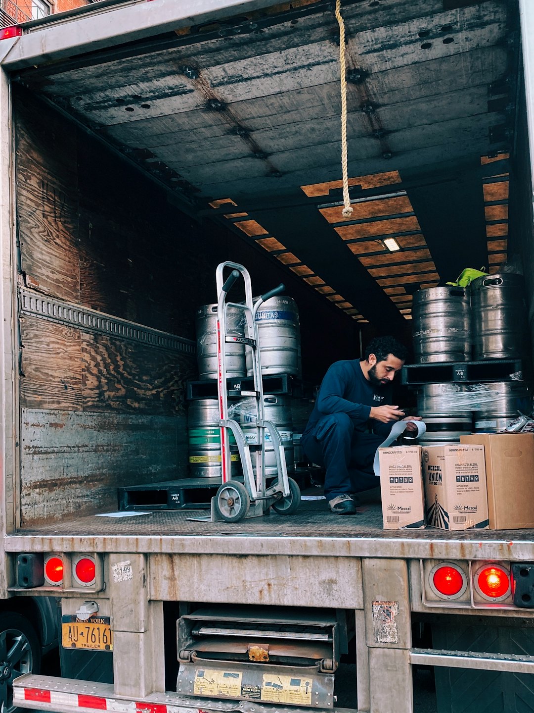 Man checking inventory of kegs in a delivery truck.