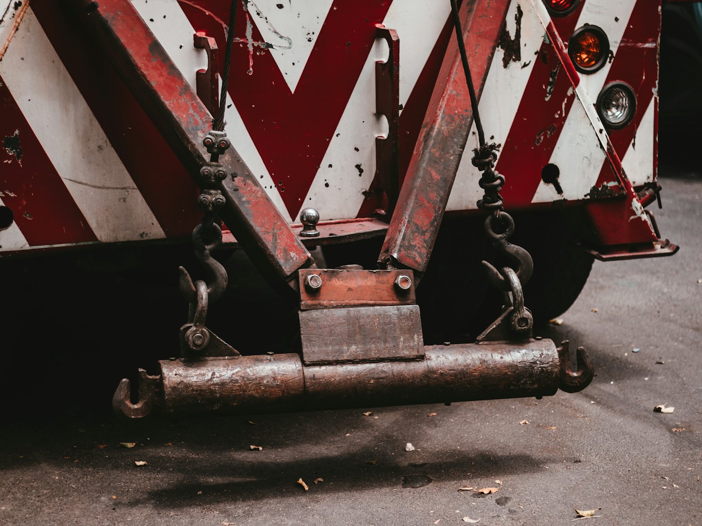 Rusty towing equipment hangs from the back of a heavy vehicle.